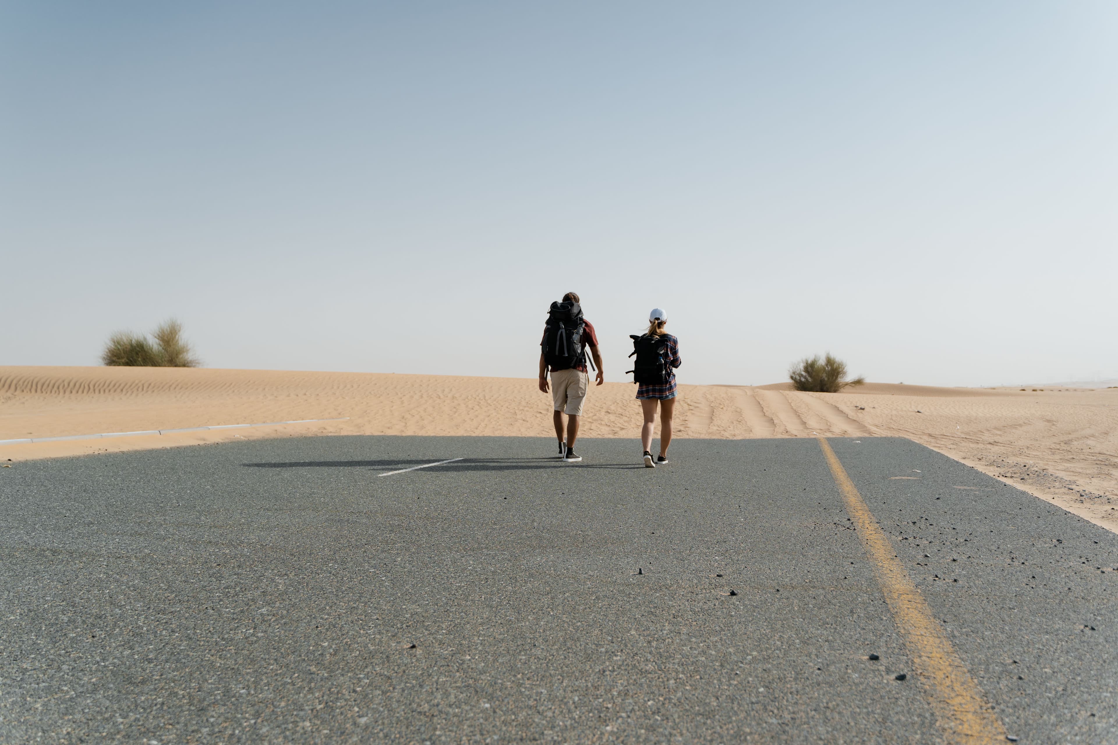 Travelers walking on an empty road through the desert