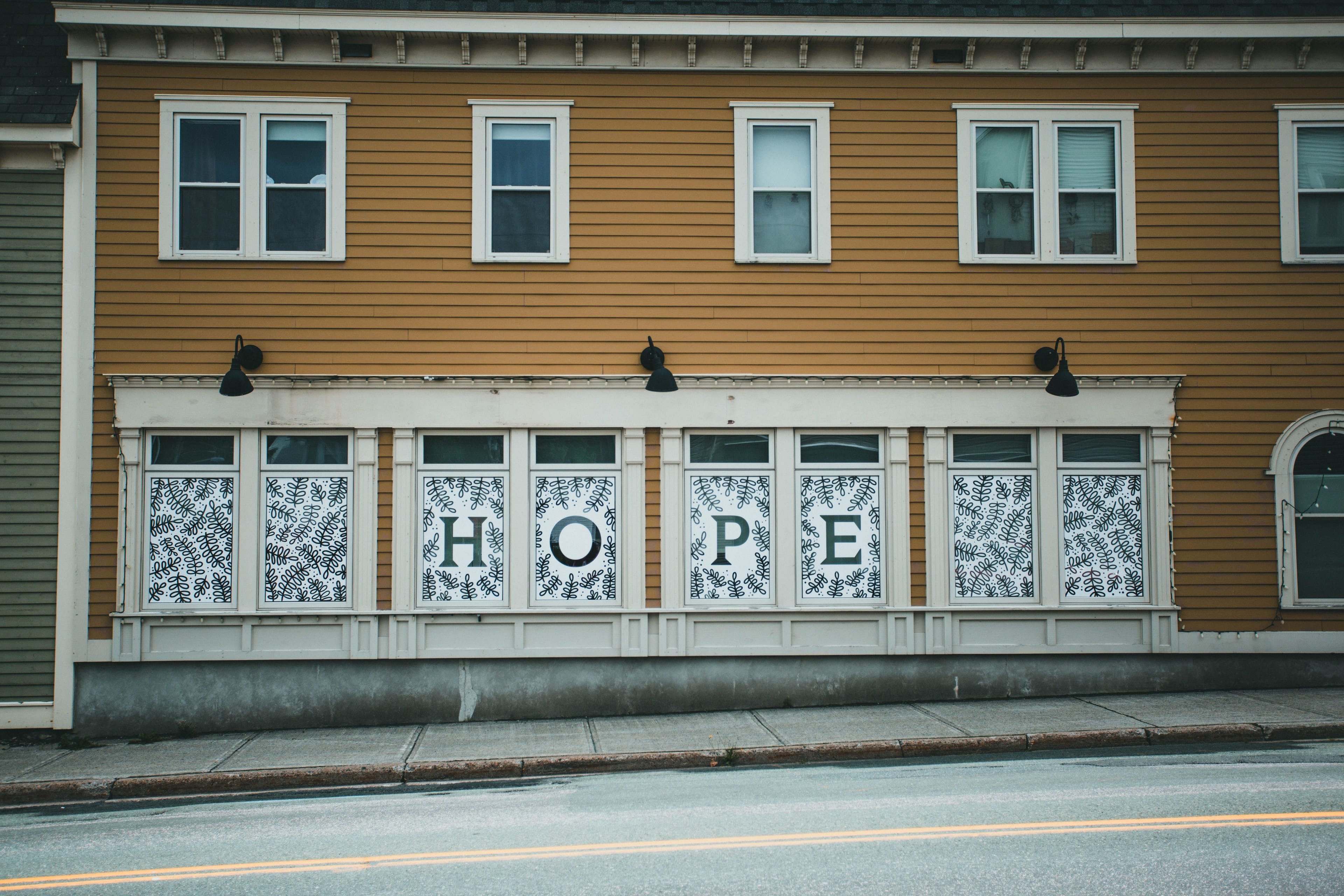 The word "HOPE" displayed across the windows of a quiet building, symbolizing optimism, expectations, and the uncertainty between hope and reality.