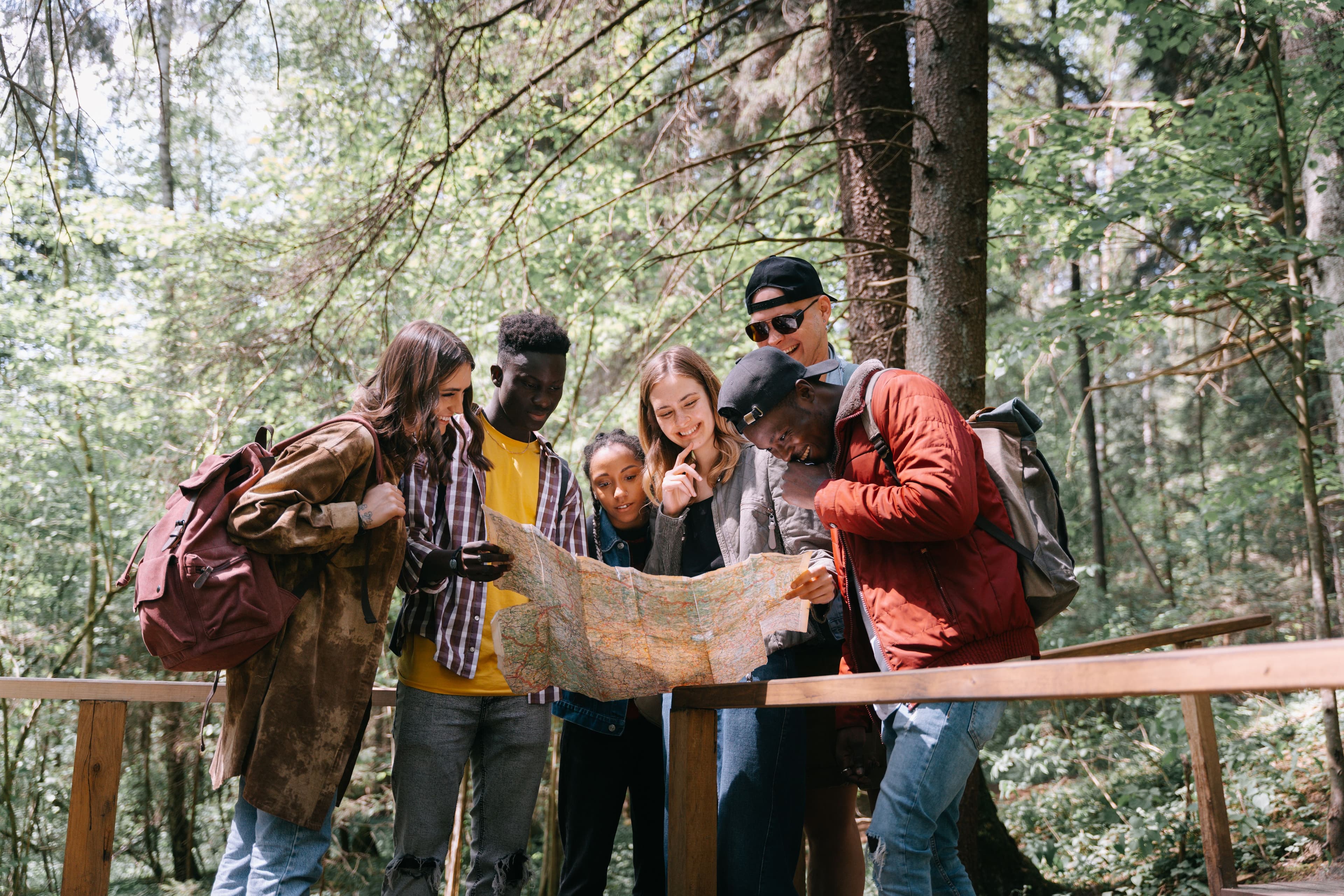 A group of friends hiking through a forest while looking at a map together.